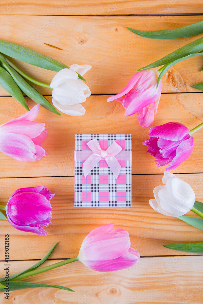 Bouquet of tender pink tulips with gift box on light wooden background Bouquet of tender pink tulips with gift box on light wooden background