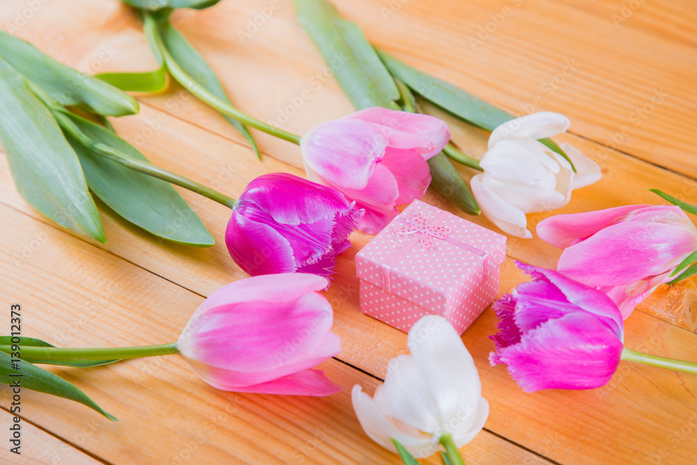 Bouquet of tender pink tulips with gift box on light wooden background Bouquet of tender pink tulips with gift box on light wooden background