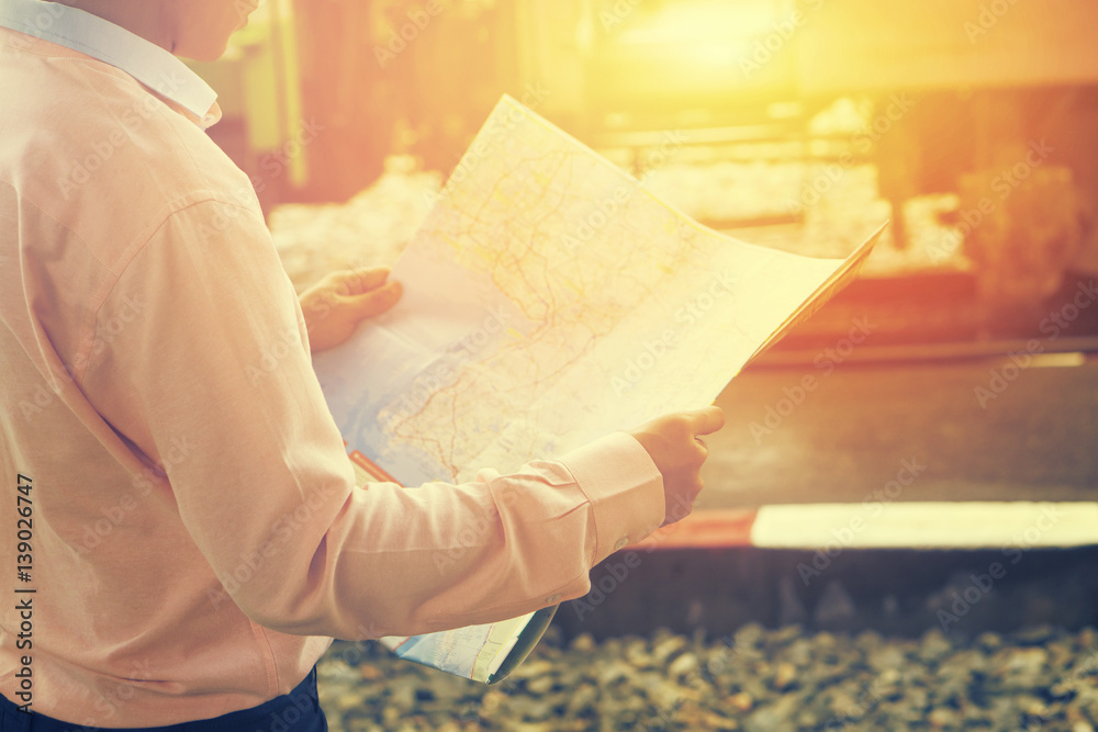 travelling concept.Relax time of businessman traveler holding location map and looking for some direction,business man holding map, waiting for a train at train station,selective focus,vintage color.