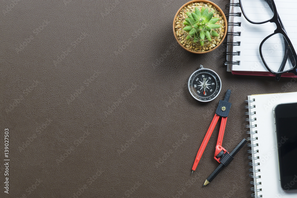 Office leather desk table with computer,supplies, cactus,glasses,circle,compass,working place elements on table,office desk table with a lot of things on it. Top view with copy space.selective focus Office leather desk table with computer,supplies, cactus,glasses,circle,compass,working place elements on table,office desk table with a lot of things on it. Top view with copy space.selective focus