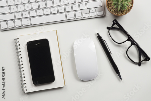 top view of working place elements on white table,Cactus,pen,,Mobile phone,Notebook,glasses,Paper, Paper Clips,with copy space.