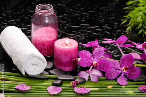 tranquil spa scene- orchid with black stones with candle  oil green plant salt in bottle