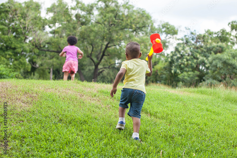 Fototapeta premium Kids running and chasing after each other in the green park in summer