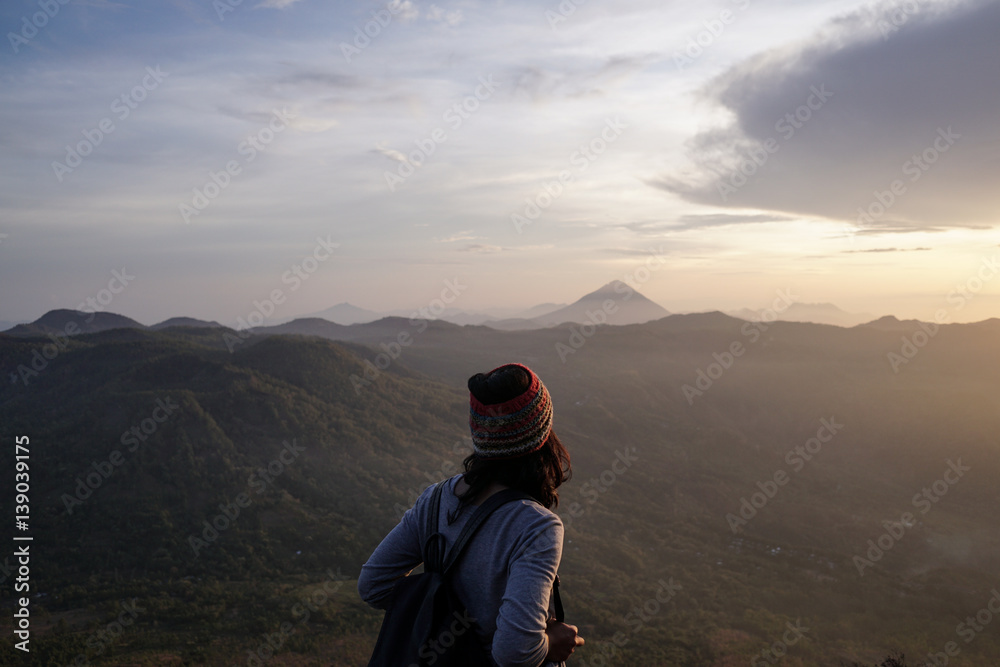 woman facing sunrise over mountain