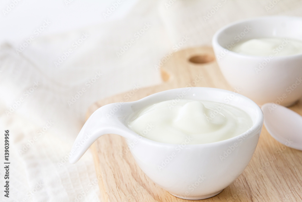 Close up natural creamy white yogurt in cup on wooden plate Close up natural creamy white yogurt in cup on wooden plate