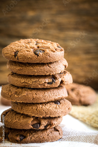Close up stacked chocolate chip cookies on  napkin with wooden background