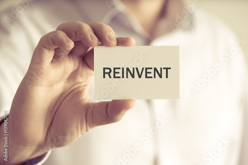 Businessman holding REINVENT message card photo