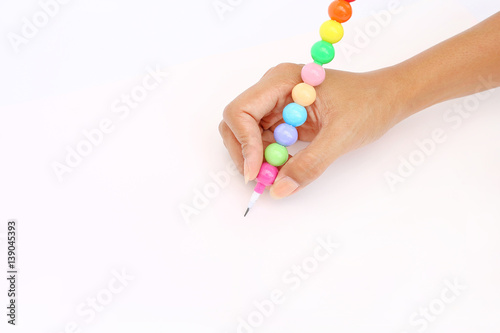 Hand holding colorful pencil on blank white paper background.