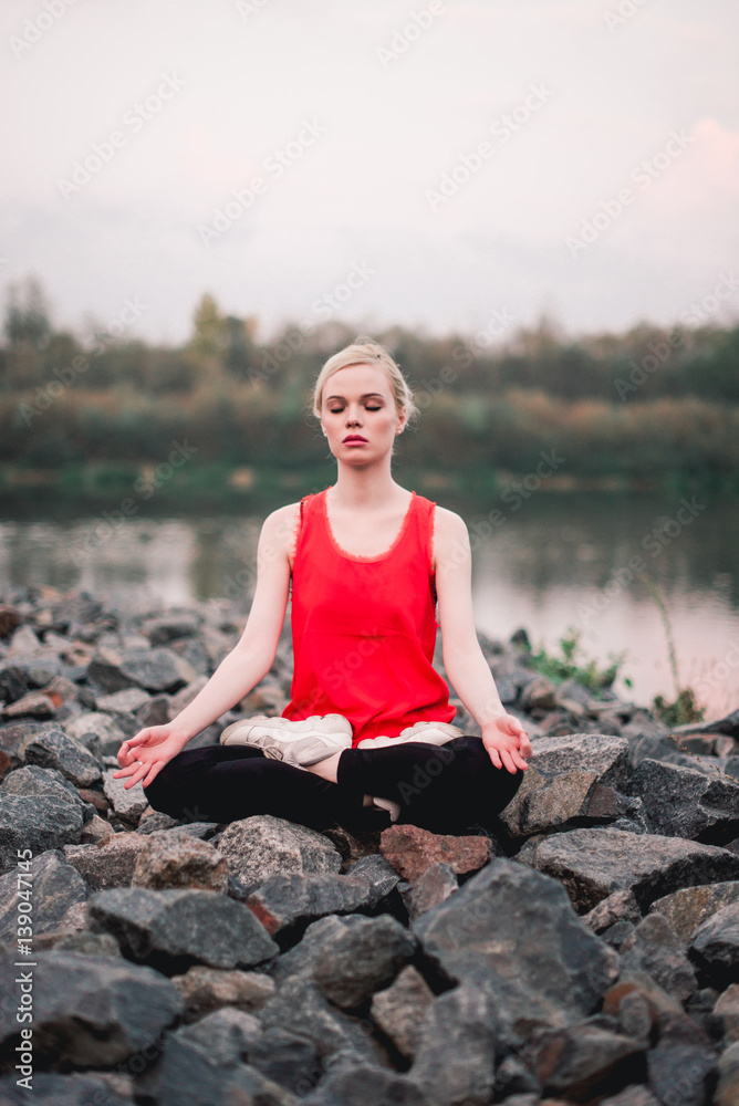 Young girl doing yoga fitness exercise outdoor near river landscape. Evening sunset, Namaste Lotus pose. Meditation and Relax