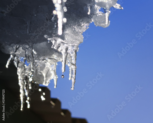 beautiful shiny icicles melt and drip on the roof in the spring