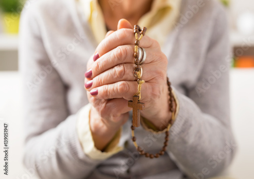 Grandma holding wooden rosary and praying
