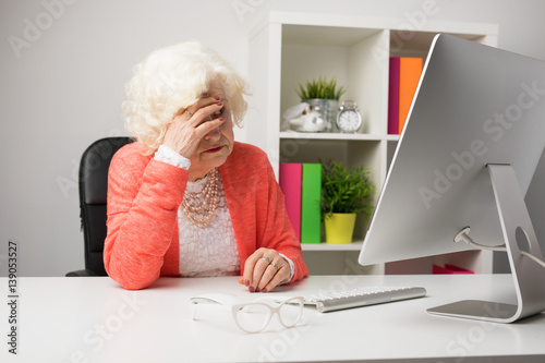 Older woman at the office don't know how to use computer