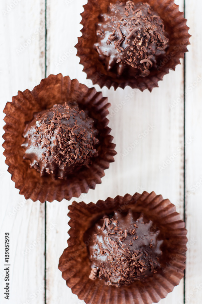 Chocolate chip muffin in brown wax paper. Unwrapped. Cocoa powder in the background Chocolate chip muffin in brown wax paper. Unwrapped. Cocoa powder in the background