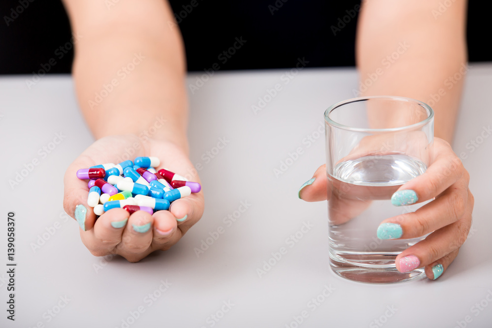 Obraz premium Young woman taking pill or drug with glass of water, health and medicine concepts, isolated on white background