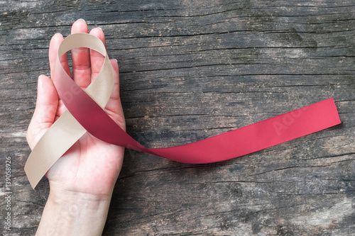 Head and neck cancer symbolic burgundy ivory white color ribbon isolated on human hand (clipping path) raising awareness help support campaign on people life living with tumor disease photo