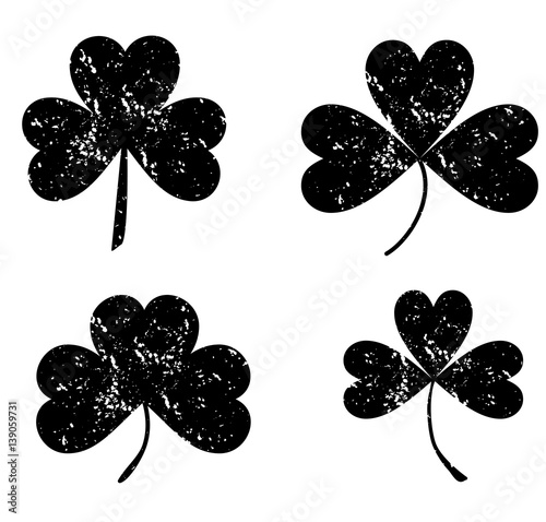 Clover leaf isolated black on white background. Silhouettes of three leaf clover in flat style with abrasion, spots and scratches. The effect of abrasion and distressed.