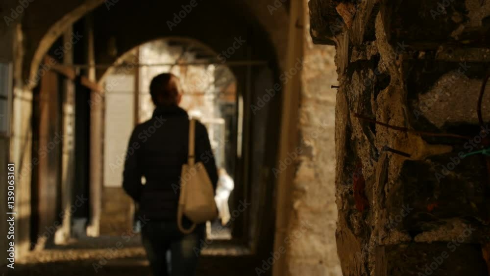 Young woman walking through the arches of the historical buildings away from the camera. Young woman walking through the arches of the historical buildings away from the camera.