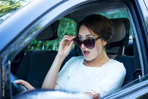 surprised girl in sunglasses driving a car