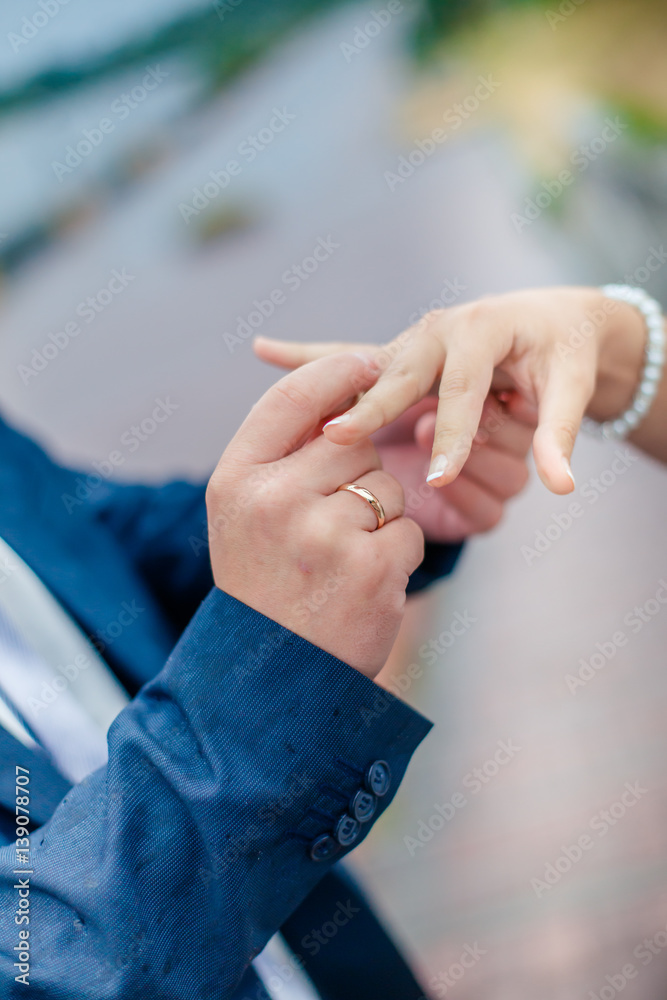 Groom wears bride a wedding ring on his finger. A couple betrothed in the street. Wedding ceremony - hands closeup.