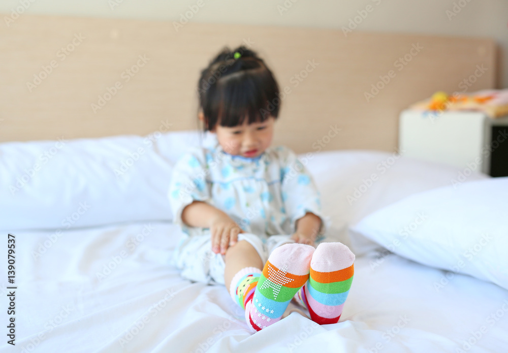 Lovely little asian girl trying to put a socks on the bed. Lovely little asian girl trying to put a socks on the bed.