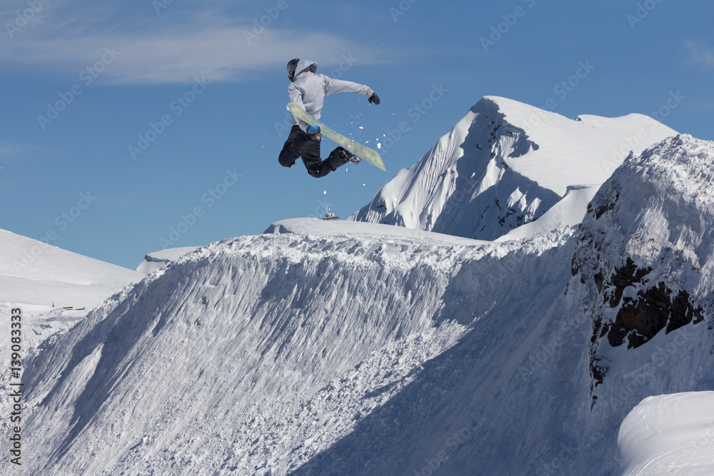Jumping snowboarder in winter mountain. Extreme sport.