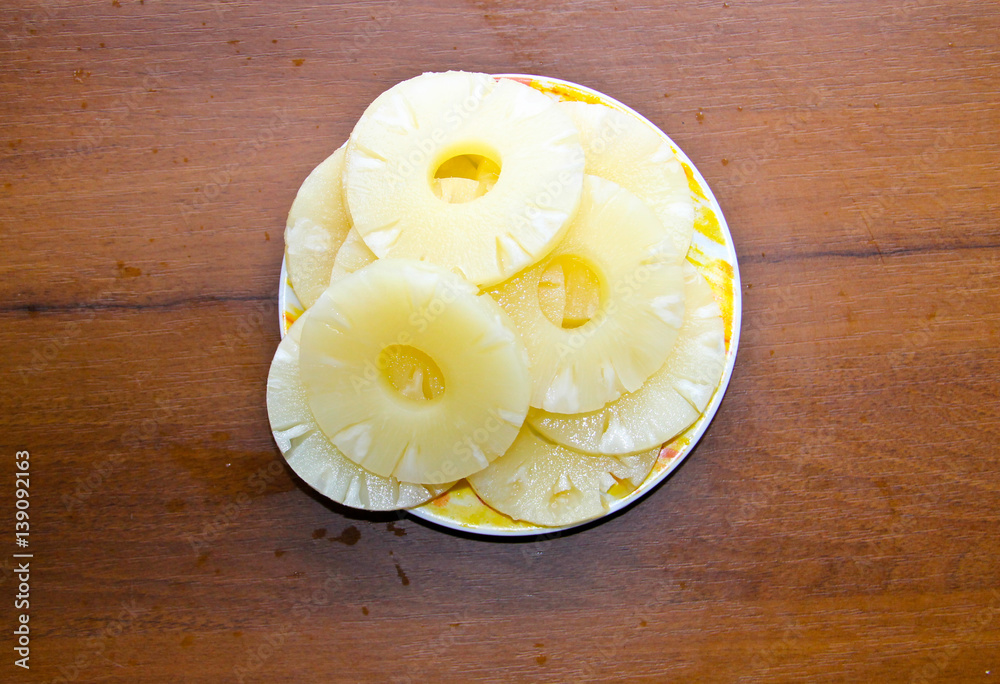 Canned pineapple on a plate on wooden table Canned pineapple on a plate on wooden table