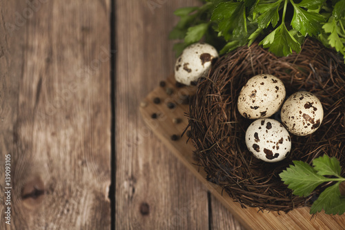 Quail eggs in a nest on a wooden background. Spices and parsley. Healthy food concept. 