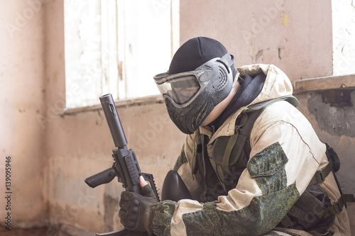 Shot of militaty man in mask with paintball weapon in his arms