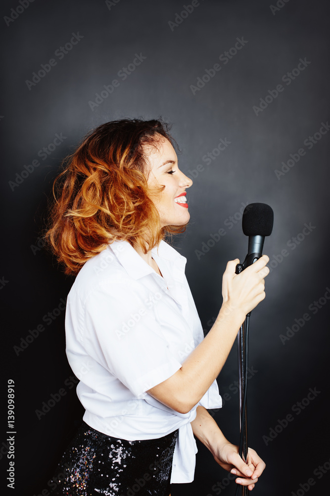 Studio portrait of woman singer with microphone in dark background Studio portrait of woman singer with microphone in dark background