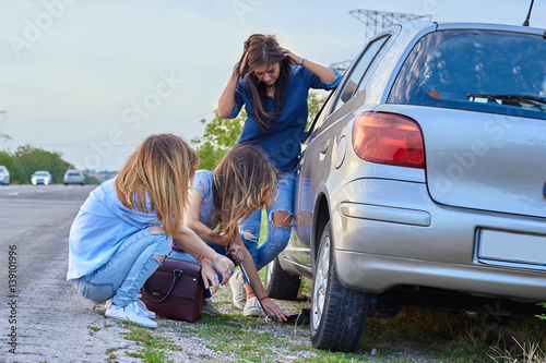 girls standing by the broken car 