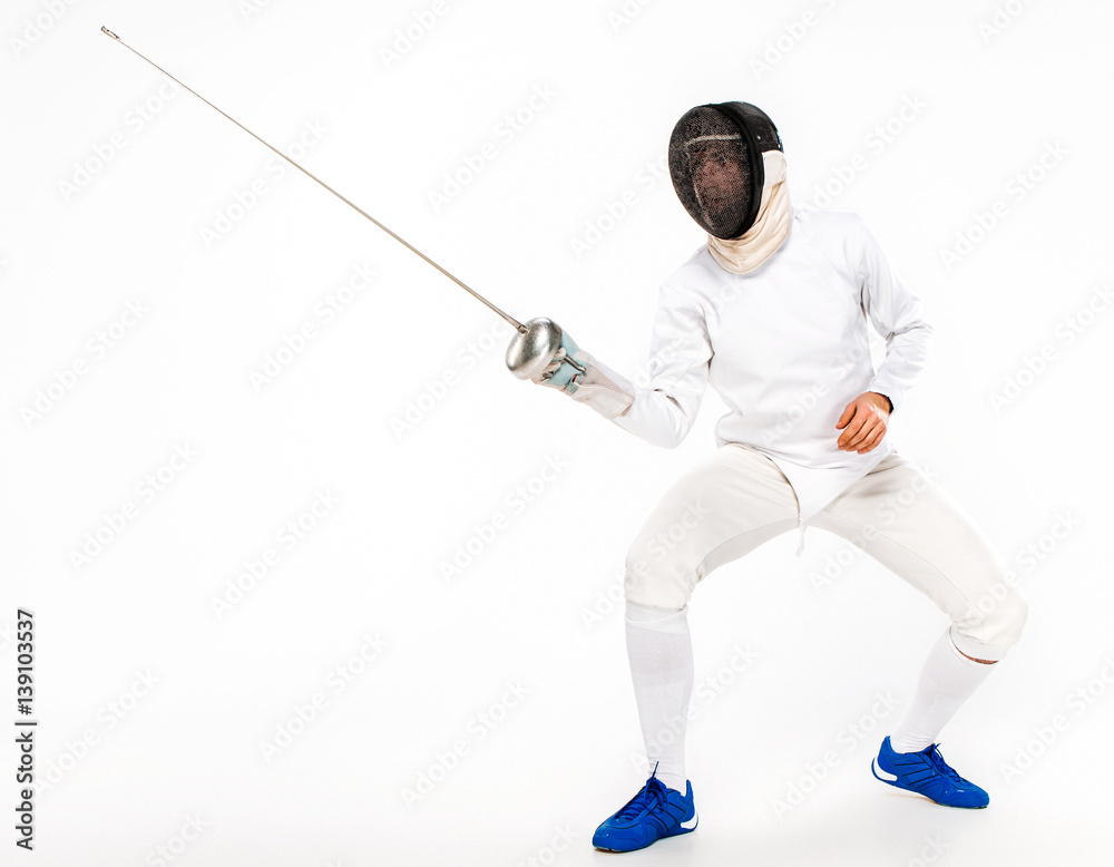 Man wearing fencing suit practicing with sword against gray Man wearing fencing suit practicing with sword against gray