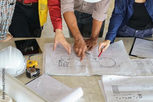 business people group on meeting and presentation with construction engineer architect looking building model and blueprint plans