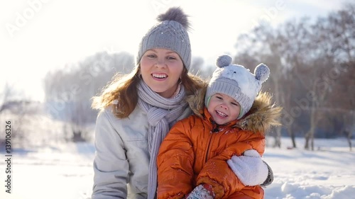 Girl plays with baby at sunny in winter time. Holding on hands