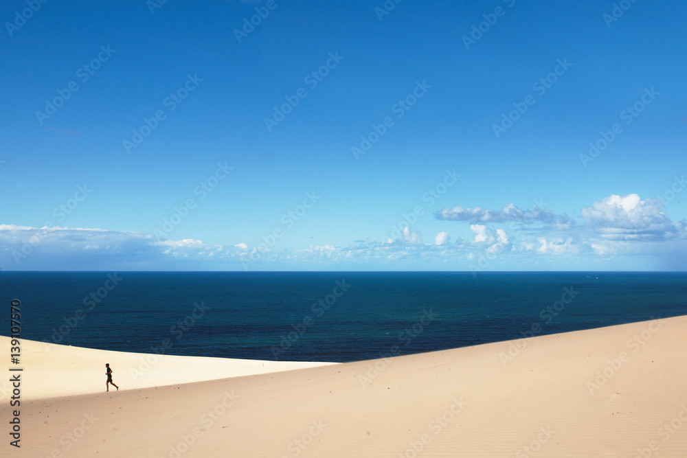 man walk alone over Dunes in a sunny day at Carlo Sandblow Rainbow Beach.