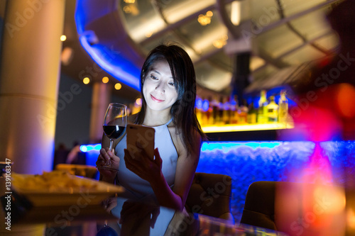 Woman using mobile phone and enjoy her drink at sky bar