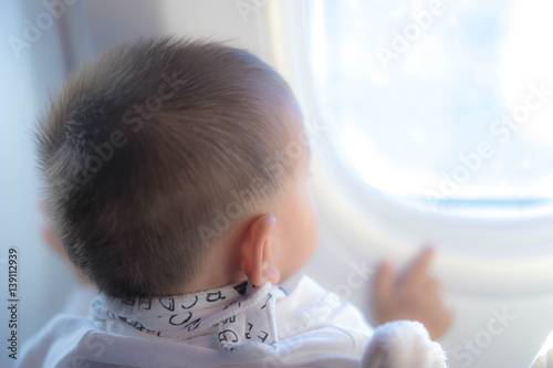 Asian baby looking out the window from airplane 