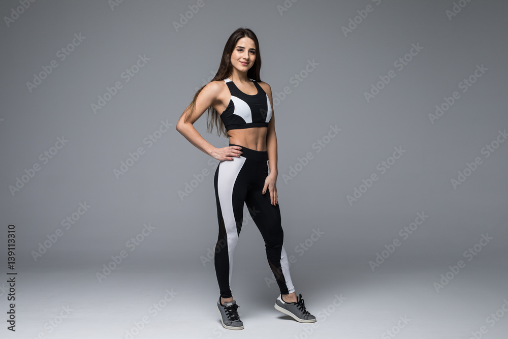 Full length portrait of a happy sporty woman over gray background. Looking at camera Full length portrait of a happy sporty woman over gray background. Looking at camera
