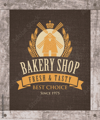 Vector banner for a bakery shop with a picture of the windmill and ears of wheat on the background of sacking and in wooden frame.