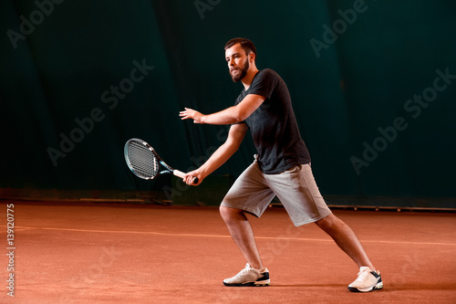 Handsome young man in t-shirt holding tennis racket on tennis court © nazarovsergey