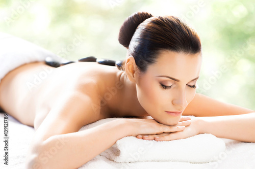 Beautiful  young and healthy woman in spa salon. Massage treatment over green summer or spring background. Traditional medicine and healing concept.