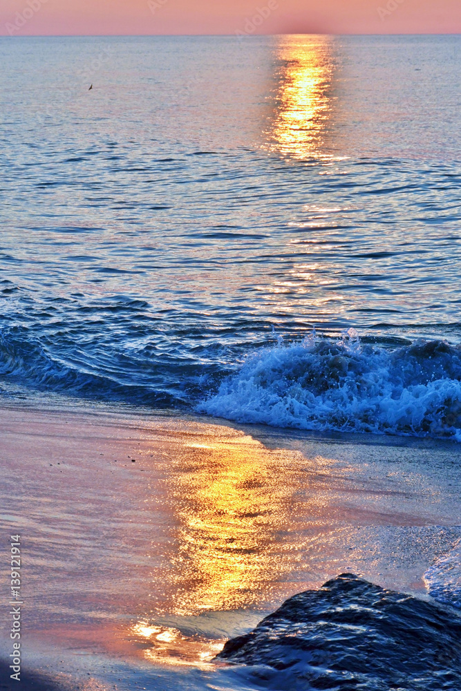 Obraz premium Golden Skies and Seas at Sunrise Above Rock Jetty on the Beach
