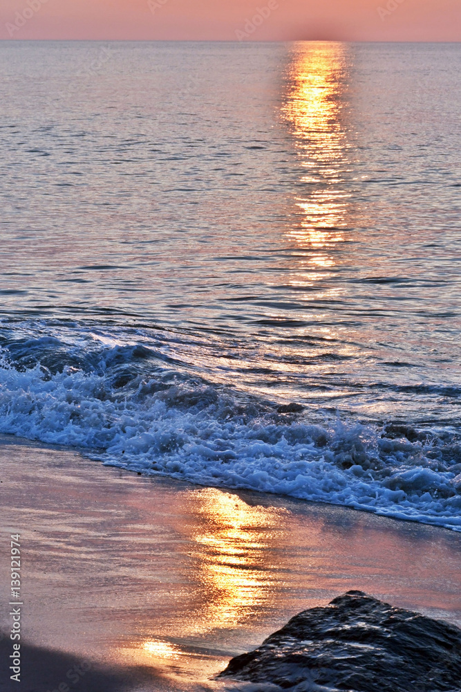 Fototapeta premium Golden Skies and Seas at Sunrise Above Rock Jetty on the Beach