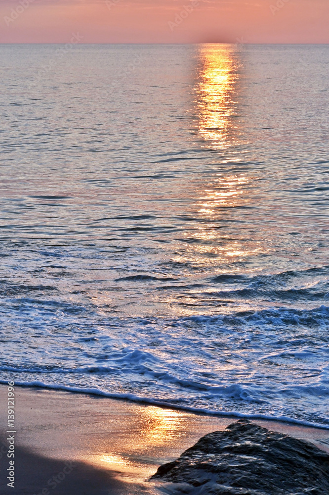 Fototapeta premium Golden Skies and Seas at Sunrise Above Rock Jetty on the Beach