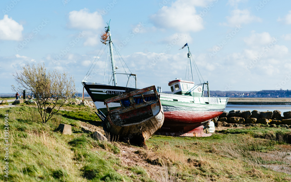 Two grounded ships in the port of Le Crotoy, in the Bay of the Somme, with blue sky with clouds.