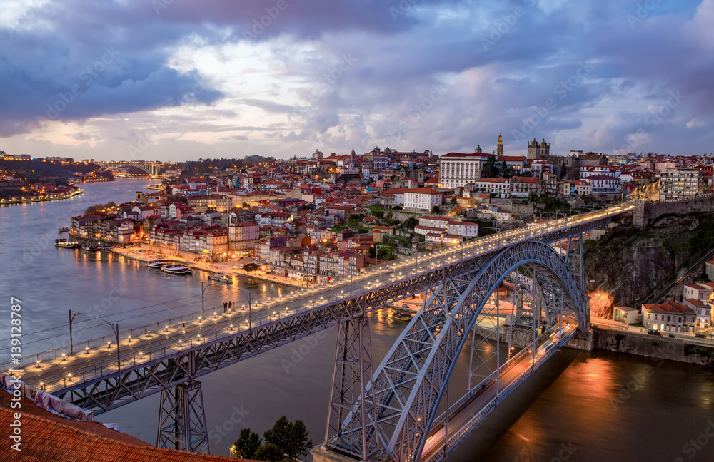 View of the historic city of Porto, Portugal with the Dom Luiz bridge at dusk.