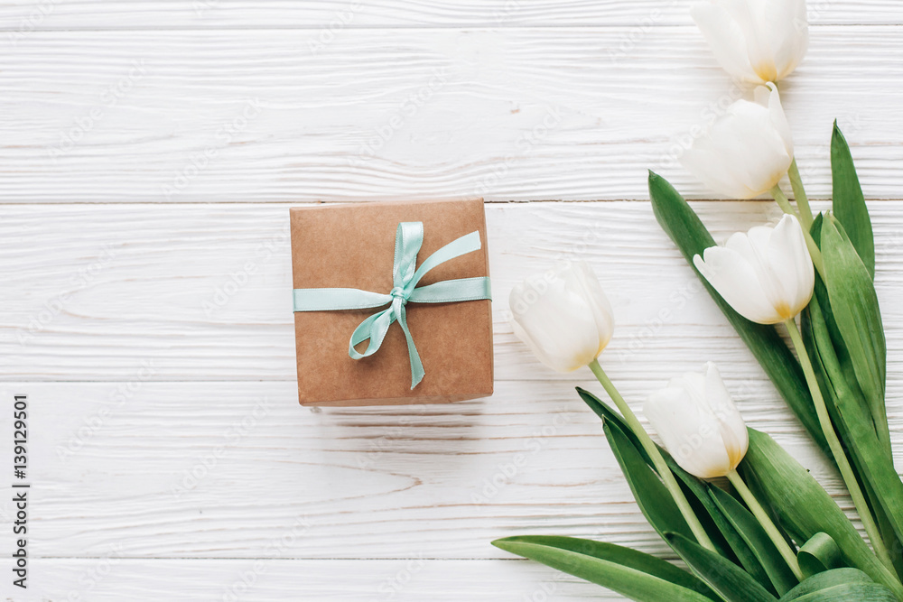 stylish craft present box and tulips on white wooden rustic background. flat lay with flowers and gift with space for text. hello spring. happy day concept. greeting card stylish craft present box and tulips on white wooden rustic background. flat lay with flowers and gift with space for text. hello spring. happy day concept. greeting card