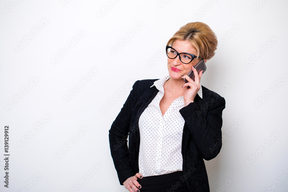 Beautiful secretary calling on the phone against a white wall Beautiful secretary calling on the phone against a white wall