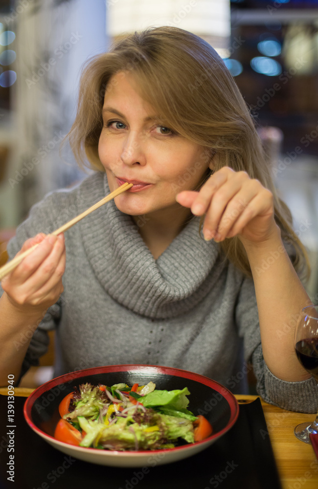 Blonde woman has dinner in japanese restuarant with sushi and drink red wine Blonde woman has dinner in japanese restuarant with sushi and drink red wine