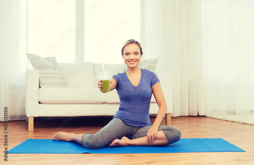 happy woman with smoothie sitting on mat at home happy woman with smoothie sitting on mat at home