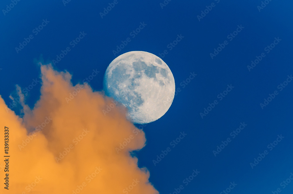 Full moon peeking out from behind the clouds, sunset sky Full moon peeking out from behind the clouds, sunset sky